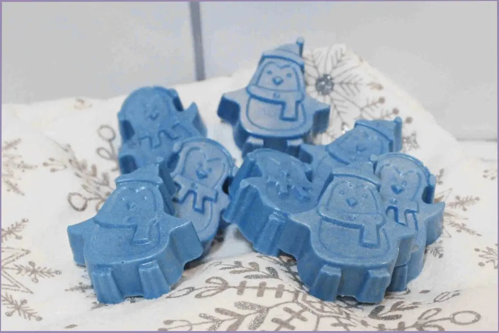 8 blue homemade penguin soap bars on a festive fabric with tips for storage and shelf life