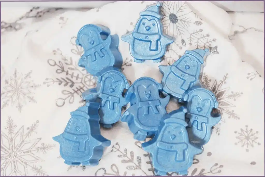 8 blue homemade penguin soap bars on a festive fabric