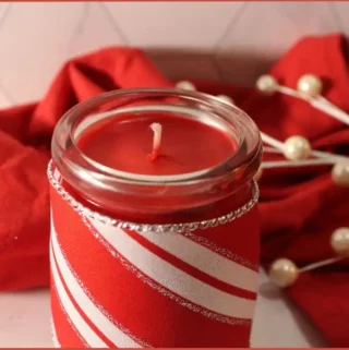 Red candle in a glass jar wrapped with red and white festive fabric - How to make a candy cane candle