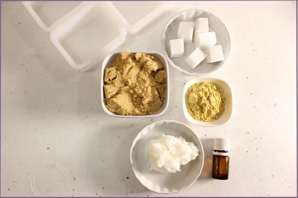 Ingredients for pumpkin spice sugar scrub bars recipe - pumpkin powder, melt and pour soap base, solid coconut oil, brown sugar, and essential oil bottle
