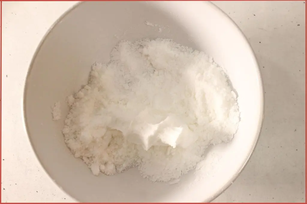 White bowl with baking soda, citric acid, and cornstarch for making bath bombs