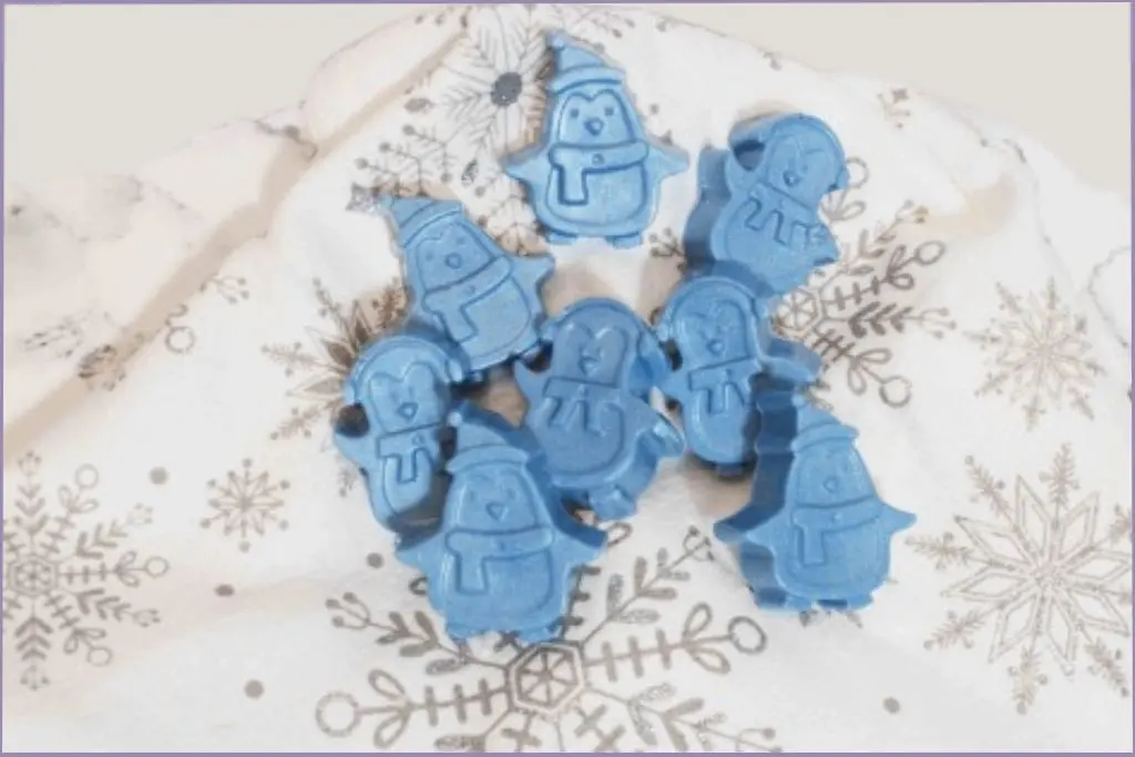 8 blue homemade penguin soap bars on a festive fabric with customization ideas