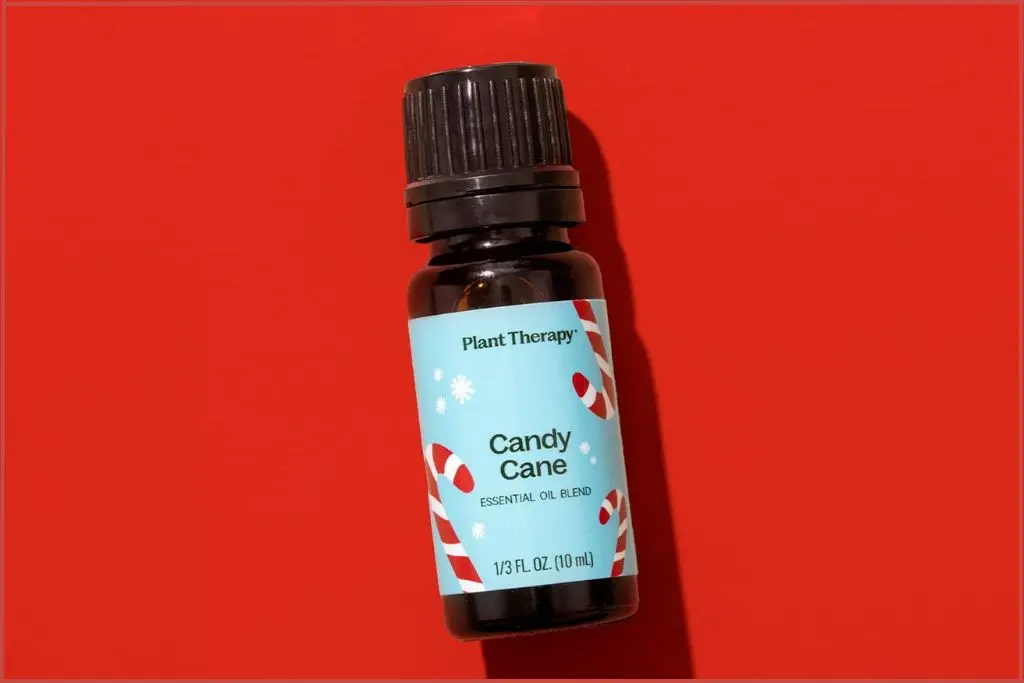 Bottle of Plant Therapy candy cane essential oil blend on a red background