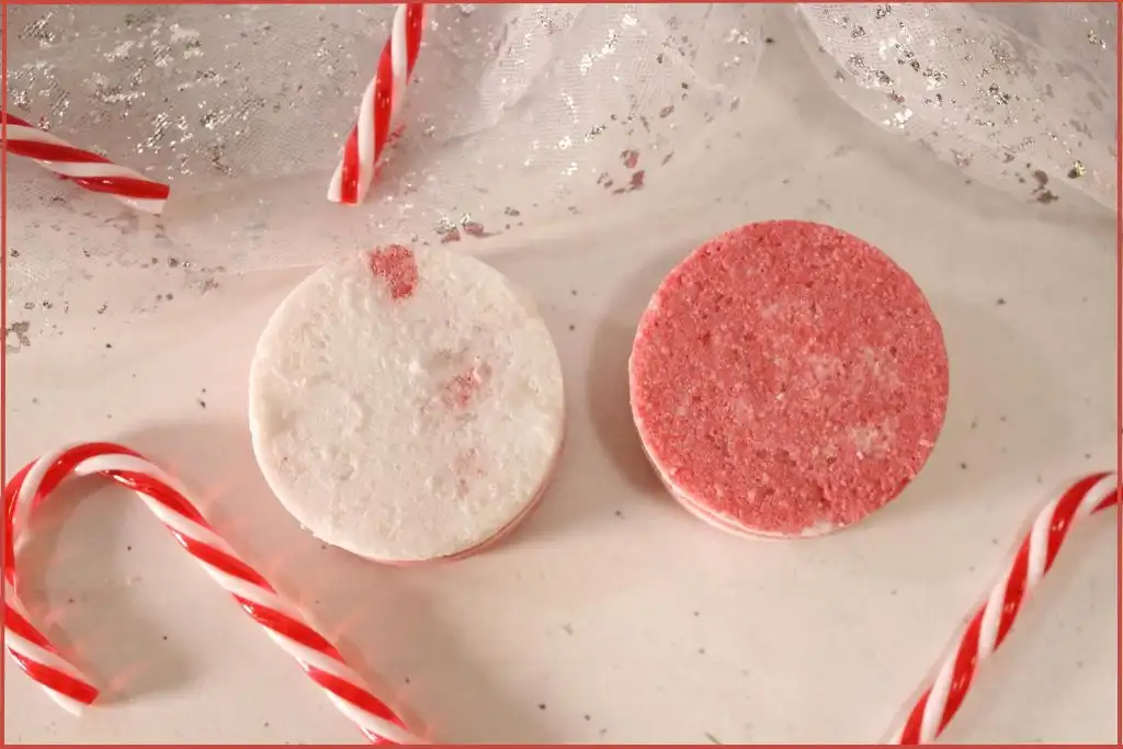 Two round red-and-white layered candy cane bath bombs on a countertop, styled with mini candy canes with trouble shooting tips.