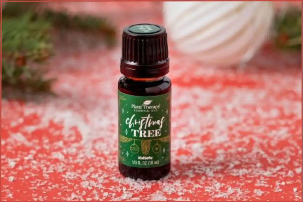 bottle of Plant Therapy Christmas tree essential oil blend on a red and white surface for scenting Christmas tree bath bombs