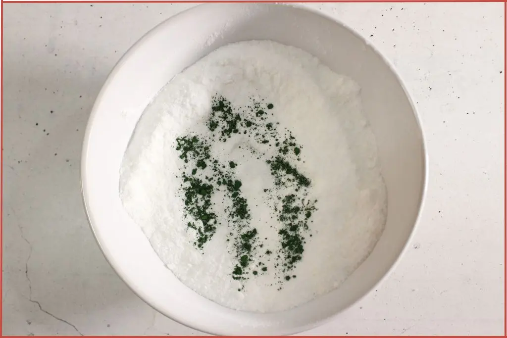 Green mica powder sprinkled on top of dry bath bomb ingredients