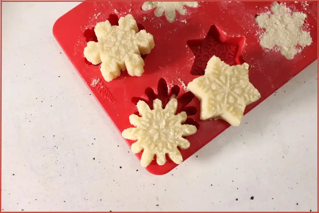 Red mold with unmolded homemade snowflake sugar scrub bars