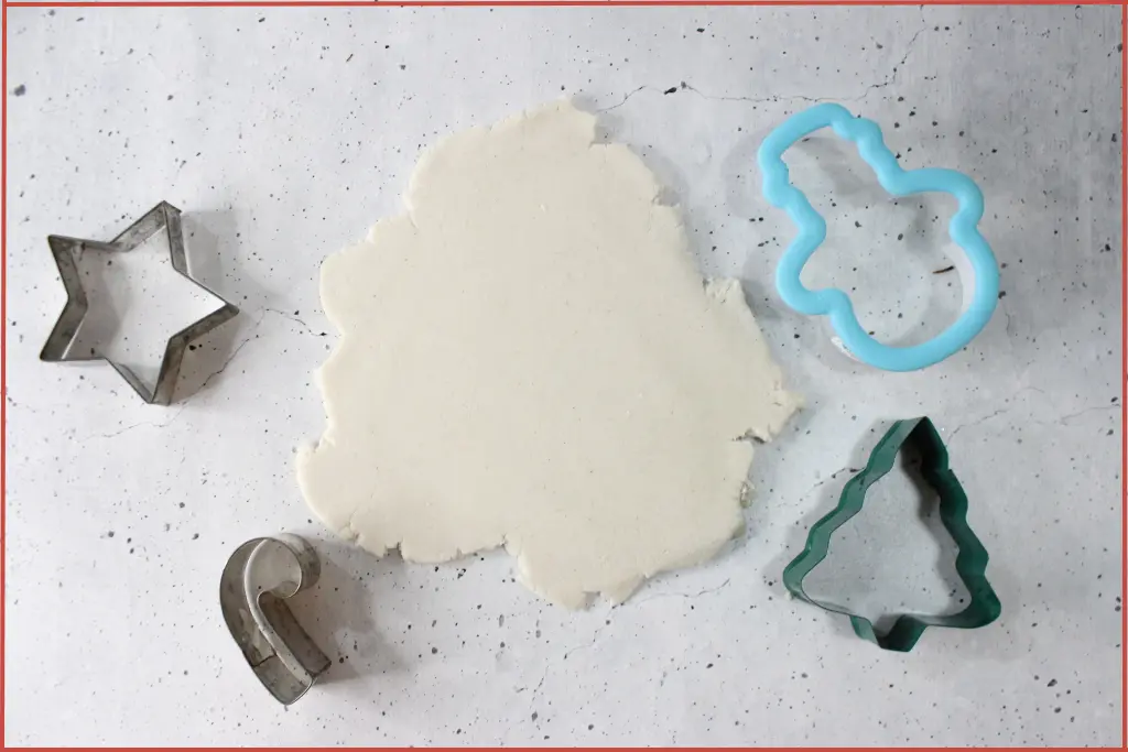 Rolled out dough with cookie cutters in Christmas shapes for making diffuser ornaments