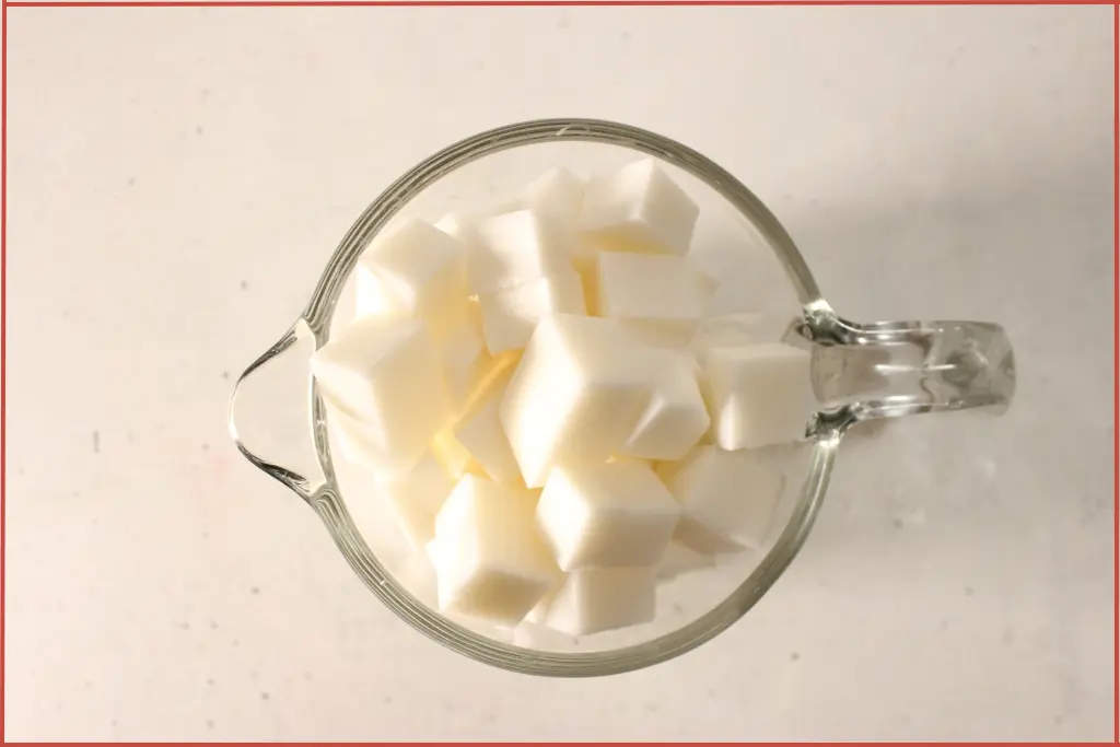 Goat's milk soap base cut into cubes and put into a glass measuring jar for melting to make candy cane soap