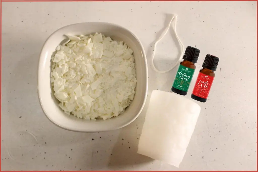Soy flakes in white bowl + snowflake candle mold, cotton wick, and two essential oil bottles