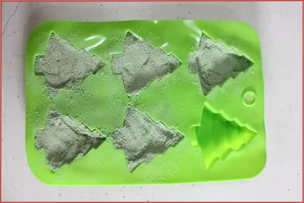 Green Christmas tree shaped mold filled with green bath bomb mixture and kept to dry on a flat surface