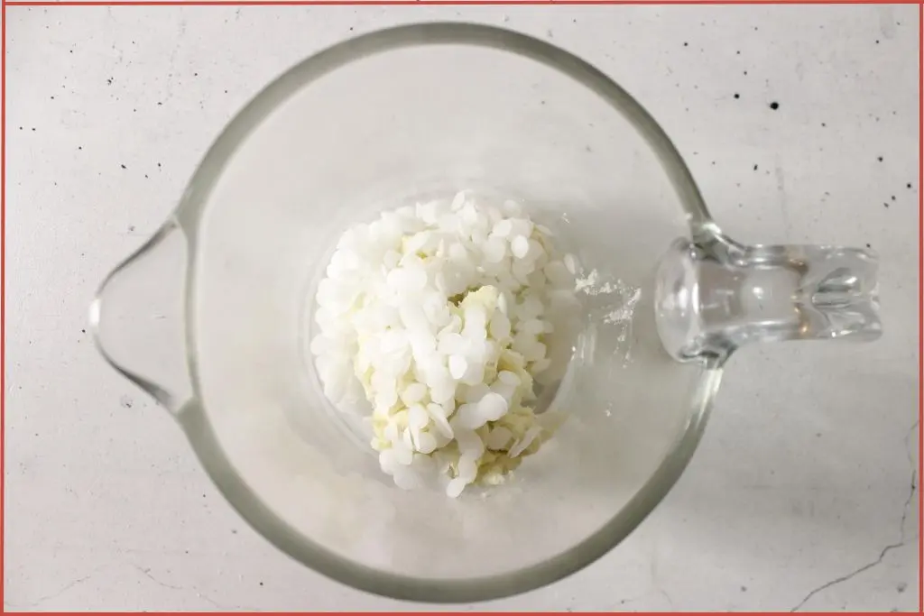 Shea butter and beeswax in a glass jar for melting to make sugar scrub bars