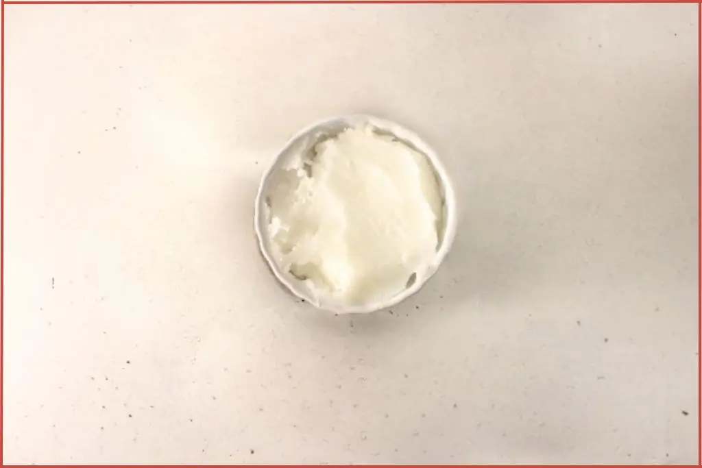 Small white bowl with solid coconut oil to be added to gingerbread sugar scrub
