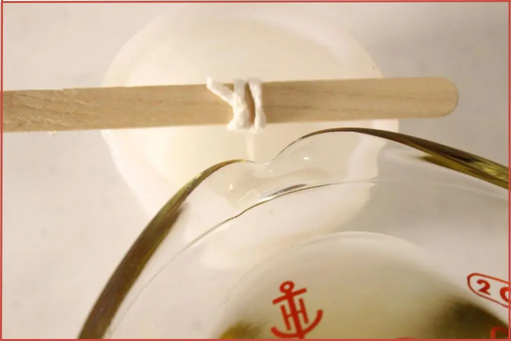 Pouring melted wax into white snowflake candle mold