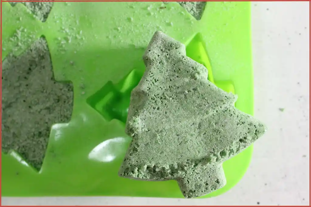 One green Christmas-tree shaped bath bomb carefully removed from the mold