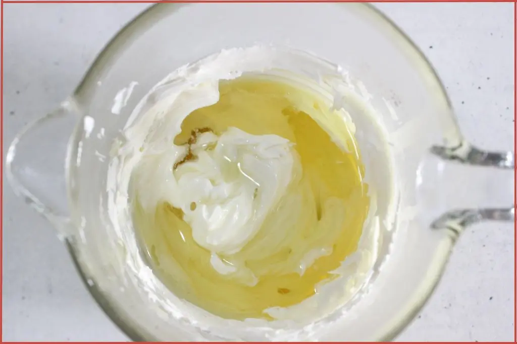 Top view of carrier oil added to solid butters in a glass measuring jar