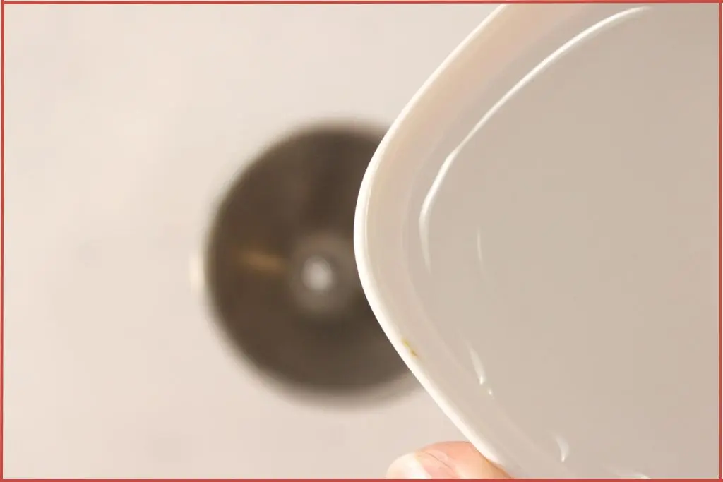 Pouring witch hazel through a funnel into a spray bottle to make Christmas room spray