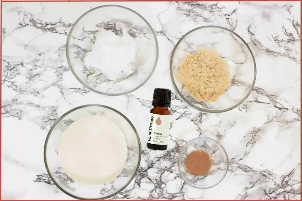 Christmas cookie sugar scrub ingredients - white sugar, brown sugar, coconut oil, cinnamon powder, and bottle of vanilla oleoresin