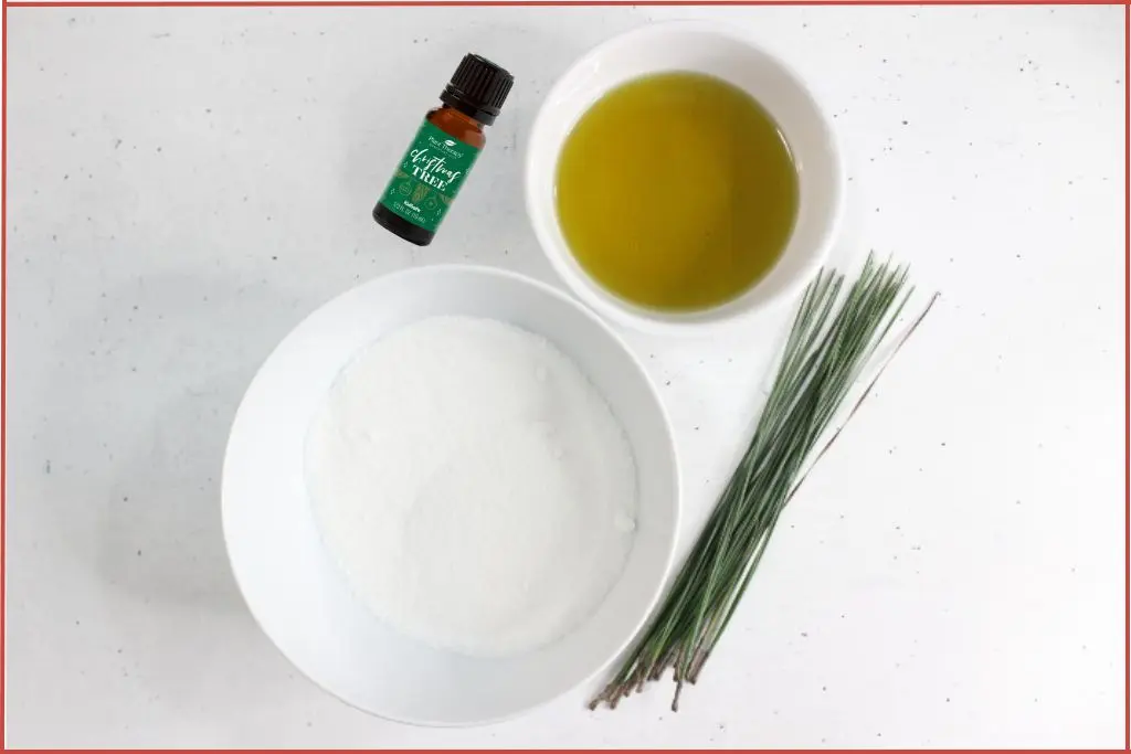 Ingredients for Christmas tree sugar scrub recipe - sugar, carrier oil, pine needles and a bottle of Christmas tree essential oil