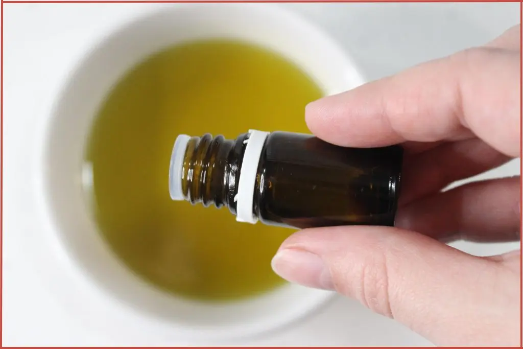 Pouring essential oil into a bowl of carrier oil to make Christmas tree sugar scrub