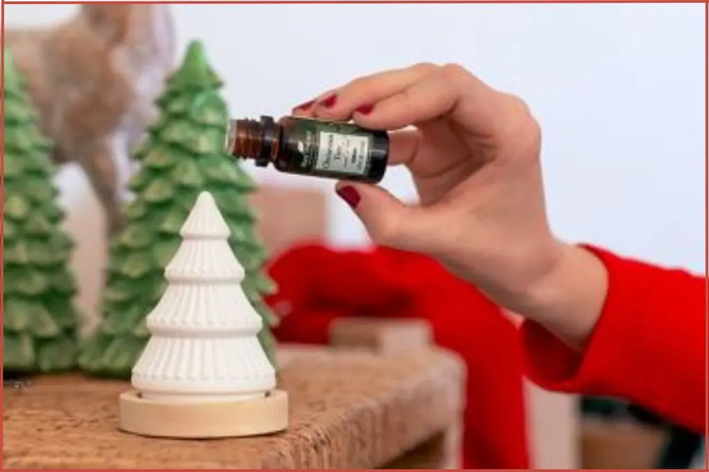 lady putting Christmas tree essential oil blend on a Christmas tree passive diffuser by Plant Therapy
