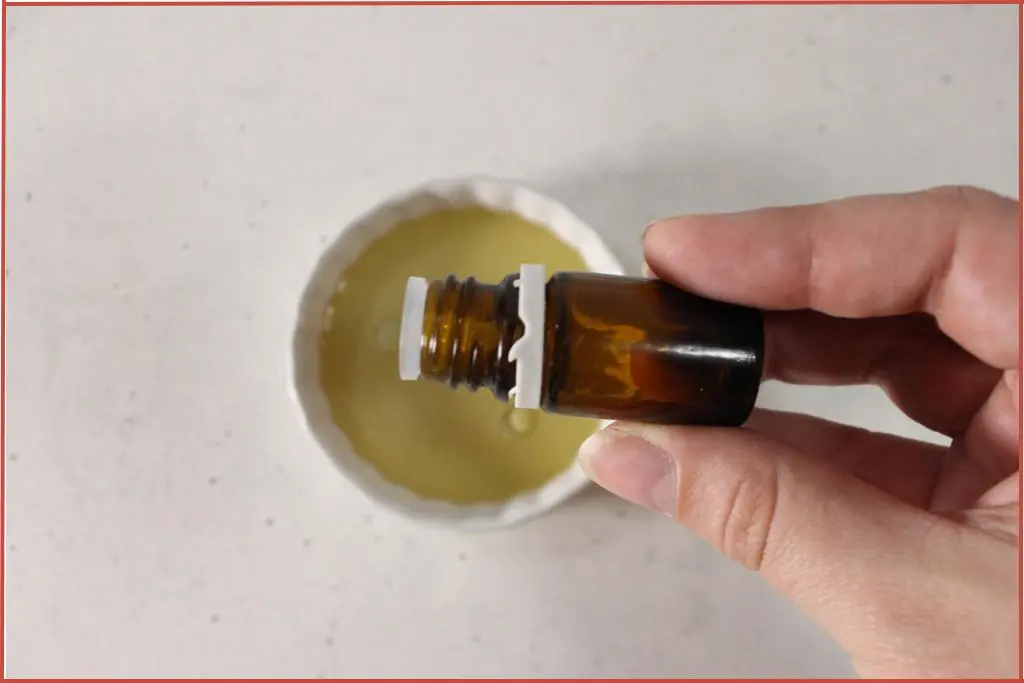 Pouring essential oil into a bowl of carrier oil before adding to homemade hand cream