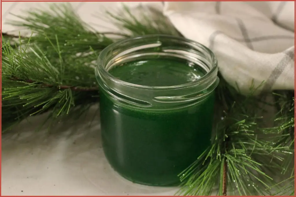 pine air freshener gal in a glass jar surrounded by pine needles and checked dish cloth