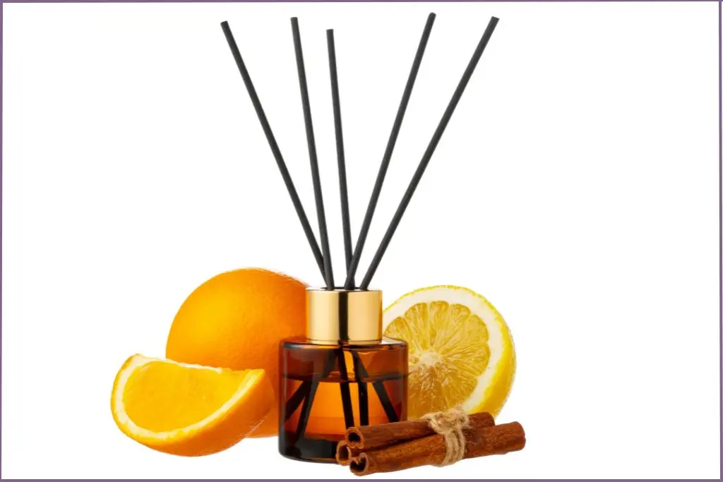 Reed diffuser with amber bottle next to citrus slices and cinnamon sticks