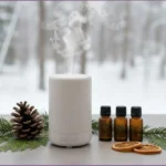 White aromatherapy diffuser misting winter forest diffuser blends, evergreen greenery, pinecone, and essential oil bottles set against a winter forest scene outside